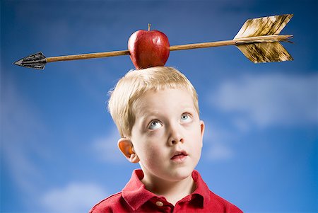 Boy with apple and arrow on head Stock Photo - Premium Royalty-Free, Code: 640-01458561