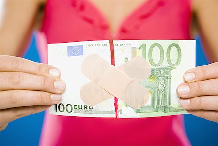 Woman with torn one hundred dollar euro banknote with plastic strips Stock Photo - Premium Royalty-Free, Code: 640-01458883