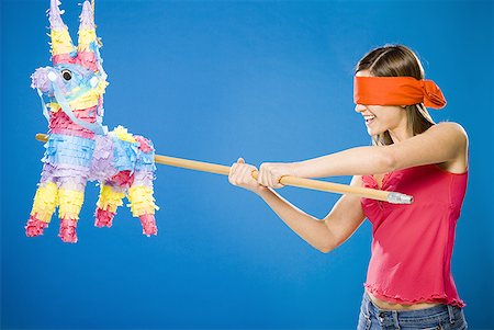 Woman with blindfold hitting pinata with stick Stock Photo - Premium Royalty-Free, Code: 640-01458906