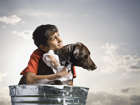 Smiling boy hugging and bathing dog outdoors on cloudy day Stock Photo - Premium Royalty-Free, Code: 640-01574898