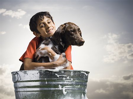 Smiling boy hugging and bathing dog outdoors on cloudy day Stock Photo - Premium Royalty-Free, Code: 640-01574899