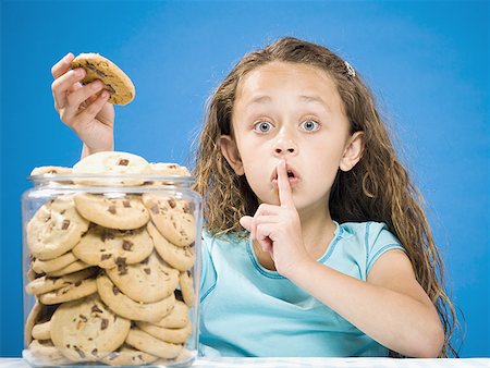 shhh - Girl taking chocolate chip cookie from jar and hushing Stock Photo - Premium Royalty-Free, Code: 640-01574928