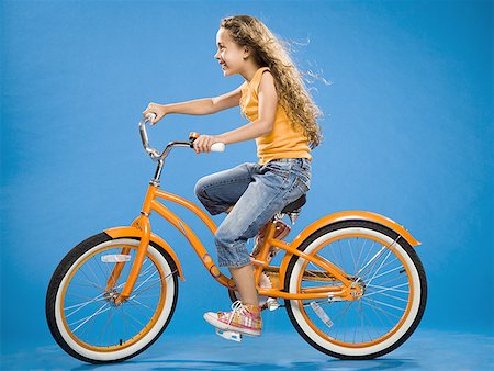 Girl riding orange bicycle profile Stock Photo - Premium Royalty-Free, Code: 640-01574942