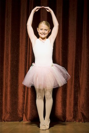 Ballerina girl standing with arms over head smiling Stock Photo - Premium Royalty-Free, Code: 640-01575007