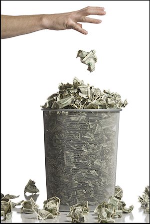 Person throwing crumpled money into waste paper basket Stock Photo - Premium Royalty-Free, Code: 640-01575039