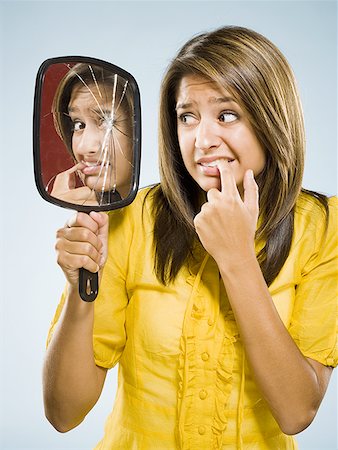 Woman looking into shattered mirror nervously Stock Photo - Premium Royalty-Free, Code: 640-01601326