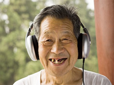 Toothless man with headphones outdoors smiling Stock Photo - Premium Royalty-Free, Code: 640-01601386