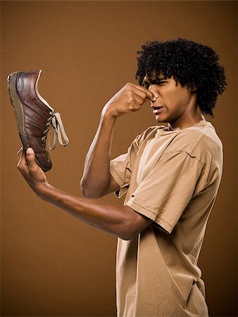 simsearch:640-02776875,k - young man in a brown shirt holding a shoe and his nose. Stock Photo - Premium Royalty-Free, Code: 640-02656870