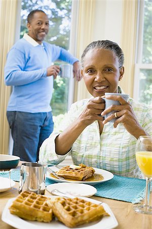 elder woman table - Portrait of a senior woman sitting at the breakfast table with a senior man standing behind her Stock Photo - Premium Royalty-Free, Code: 640-02764583