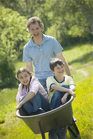 simsearch:640-02767291,k - Man pushing his son and daughter in a wheelbarrow Stock Photo - Premium Royalty-Free, Code: 640-02764643