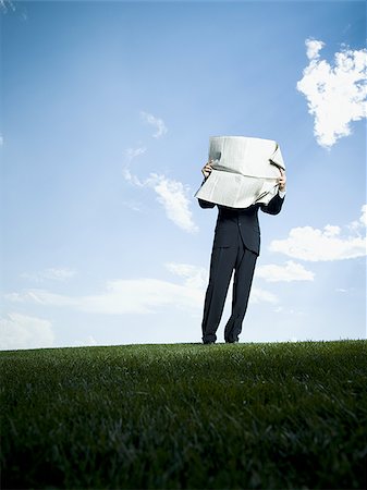 Businessman standing on the grass and reading a newspaper Stock Photo - Premium Royalty-Free, Code: 640-02764766