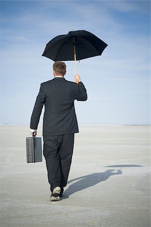 future of the desert - Rear view of a businessman walking and holding an umbrella Stock Photo - Premium Royalty-Free, Code: 640-02766705