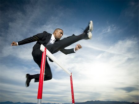 Low angle view of a businessman jumping over a hurdle in a race Stock Photo - Premium Royalty-Free, Code: 640-02766709