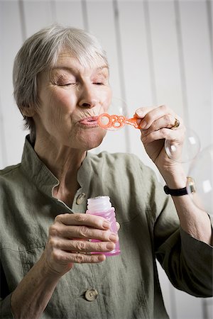 simsearch:640-02768330,k - Portrait of an elderly woman blowing bubbles with a bubble wand Stock Photo - Premium Royalty-Free, Code: 640-02767050