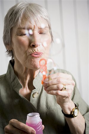simsearch:640-02768330,k - Portrait of an elderly woman blowing bubbles with a bubble wand Stock Photo - Premium Royalty-Free, Code: 640-02767051