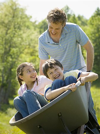 propulsion - man pushing his son and daughter in a wheelbarrow Stock Photo - Premium Royalty-Free, Code: 640-02767293