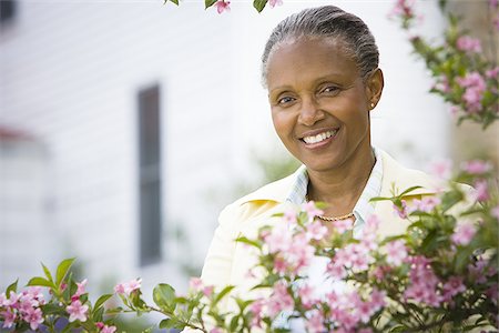 Portrait of a mature woman smiling behind flowers Stock Photo - Premium Royalty-Free, Code: 640-02767411