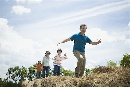 simsearch:640-02767192,k - Low angle view of a man and a woman jumping with their children on hay bales Foto de stock - Sin royalties Premium, Código: 640-02767582