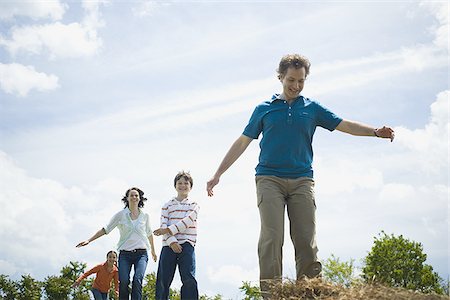 simsearch:640-02767192,k - Low angle view of a man and a woman jumping with their children on hay bales Foto de stock - Sin royalties Premium, Código: 640-02767583