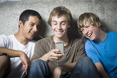 simsearch:640-02767760,k - Gros plan de trois jeunes garçons regardant un lecteur MP3 Photographie de stock - Premium Libres de Droits, Code: 640-02767759
