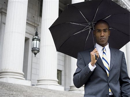 simsearch:640-02767805,k - Portrait of a male lawyer standing in front of a courthouse and holding an umbrella Stock Photo - Premium Royalty-Free, Code: 640-02767783