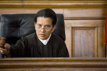 Portrait of a female judge holding a gavel and looking serious Stock Photo - Premium Royalty-Free, Code: 640-02767838