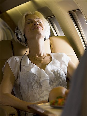 simsearch:640-01350298,k - A businesswoman listening to music from an MP3 player in an airplane Stock Photo - Premium Royalty-Free, Code: 640-02767950
