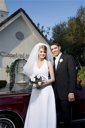 Portrait of a newlywed couple standing near a car in front of a chapel Stock Photo - Premium Royalty-Free, Code: 640-02768017