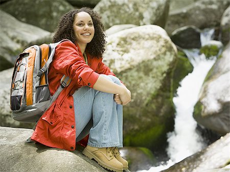 simsearch:632-05604251,k - Portrait d'une jeune femme assise sur un rocher et souriant Photographie de stock - Premium Libres de Droits, Code: 640-02768249