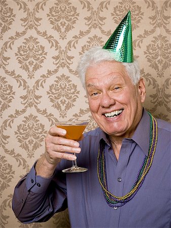 simsearch:640-02768330,k - Portrait of a senior man holding a glass of martini and wearing a party hat Stock Photo - Premium Royalty-Free, Code: 640-02768341