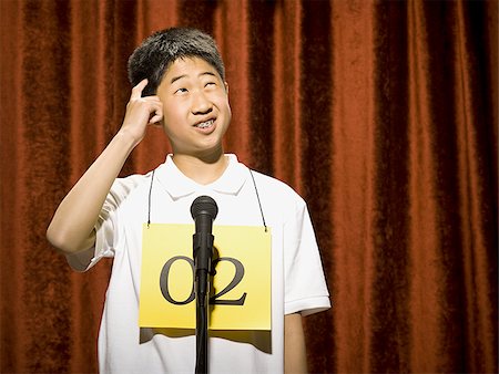 Boy contestant standing at microphone thinking Stock Photo - Premium Royalty-Free, Code: 640-02774533