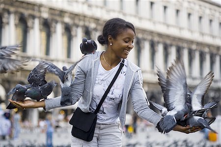 depth of field - Woman in public square with pigeons smiling Stock Photo - Premium Royalty-Free, Code: 640-02775443