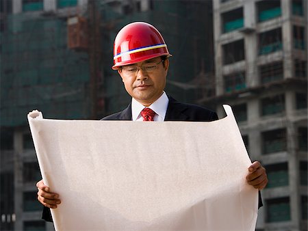 Construction site foreman with blueprints outdoors Stock Photo - Premium Royalty-Free, Code: 640-02775506