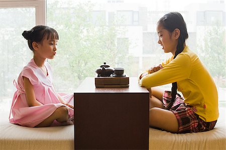 Profile of two girls sitting cross legged having tea Stock Photo - Premium Royalty-Free, Code: 640-02775629