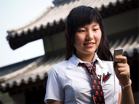 Teenage girl in school uniform smiling with mp3 player Stock Photo - Premium Royalty-Free, Code: 640-02775680