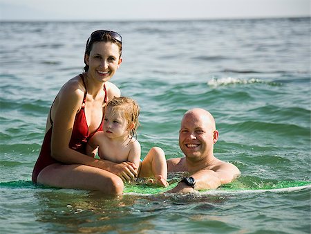 simsearch:640-02776663,k - Family in the ocean on a surfboard. Stock Photo - Premium Royalty-Free, Code: 640-02776657