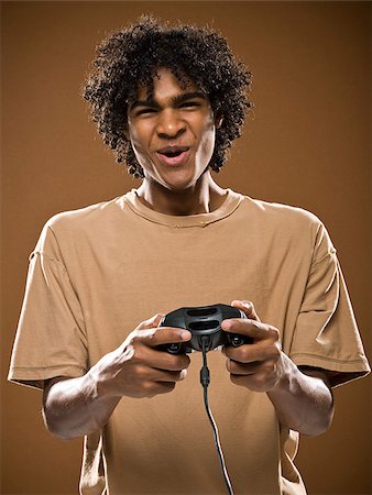 simsearch:640-02776875,k - young man in a brown shirt playing a video game. Stock Photo - Premium Royalty-Free, Code: 640-02776868