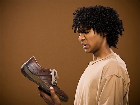 simsearch:640-02776875,k - young man in a brown shirt holding a shoe and his nose. Stock Photo - Premium Royalty-Free, Code: 640-02776876