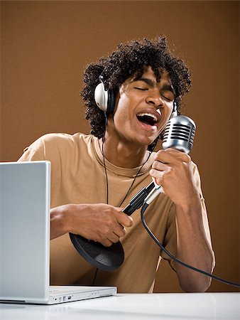 simsearch:640-02776875,k - young man in a brown shirt on a laptop with headphones and a microphone. Stock Photo - Premium Royalty-Free, Code: 640-02776893