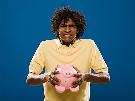 simsearch:640-02776875,k - young man trying to get money out of a piggy bank. Stock Photo - Premium Royalty-Free, Code: 640-02776924