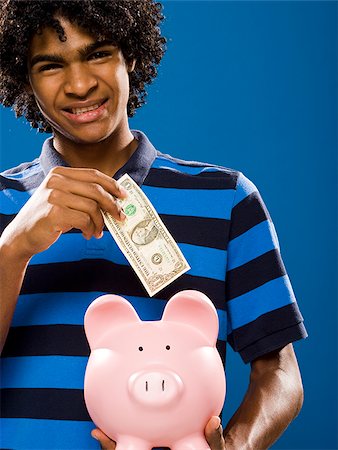 simsearch:640-02776875,k - young man putting money in a piggy bank. Stock Photo - Premium Royalty-Free, Code: 640-02776921