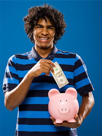 simsearch:640-02776875,k - young man putting money in a piggy bank. Stock Photo - Premium Royalty-Free, Code: 640-02776922
