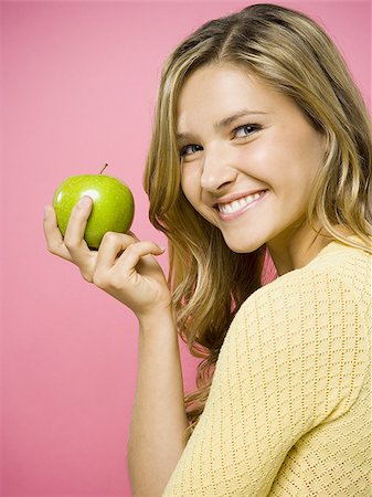 Woman smiling with green apple Stock Photo - Premium Royalty-Free, Code: 640-02771446