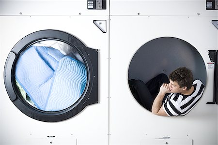 Man in dryer watching laundry Stock Photo - Premium Royalty-Free, Code: 640-02771603