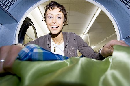 Inside dryer at Laundromat with woman removing clothing Stock Photo - Premium Royalty-Free, Code: 640-02771616
