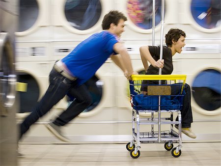 Young couple on trolley at Laundromat having fun Stock Photo - Premium Royalty-Free, Code: 640-02771653