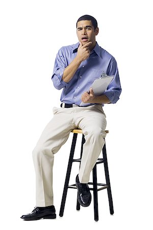 Man sitting on stool with clipboard gesturing Stock Photo - Premium Royalty-Free, Code: 640-02771860