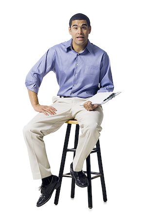 Man sitting on stool with clipboard gesturing Stock Photo - Premium Royalty-Free, Code: 640-02771861