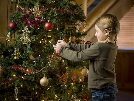 Girl with Christmas bauble and Christmas tree Stock Photo - Premium Royalty-Free, Code: 640-02771983