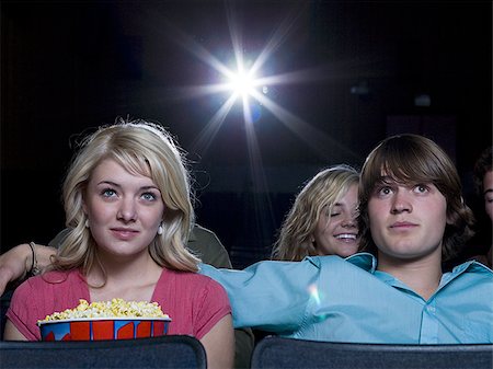 simsearch:640-02773406,k - Boy reaching arm out behind girl with popcorn at movie theater Stock Photo - Premium Royalty-Free, Code: 640-02773390